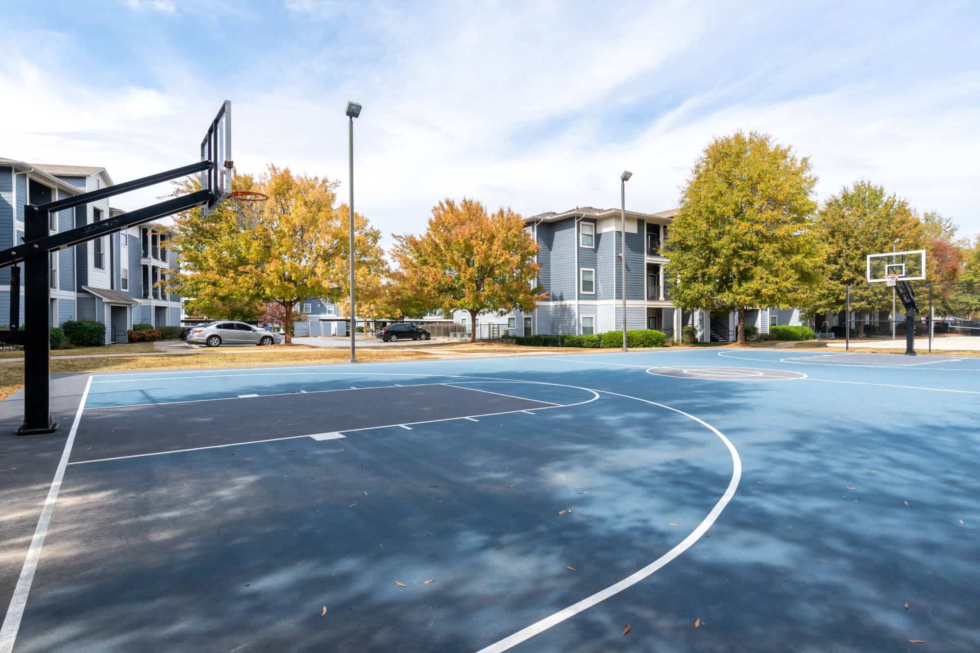 Lighted basketball court in autumn setting.
